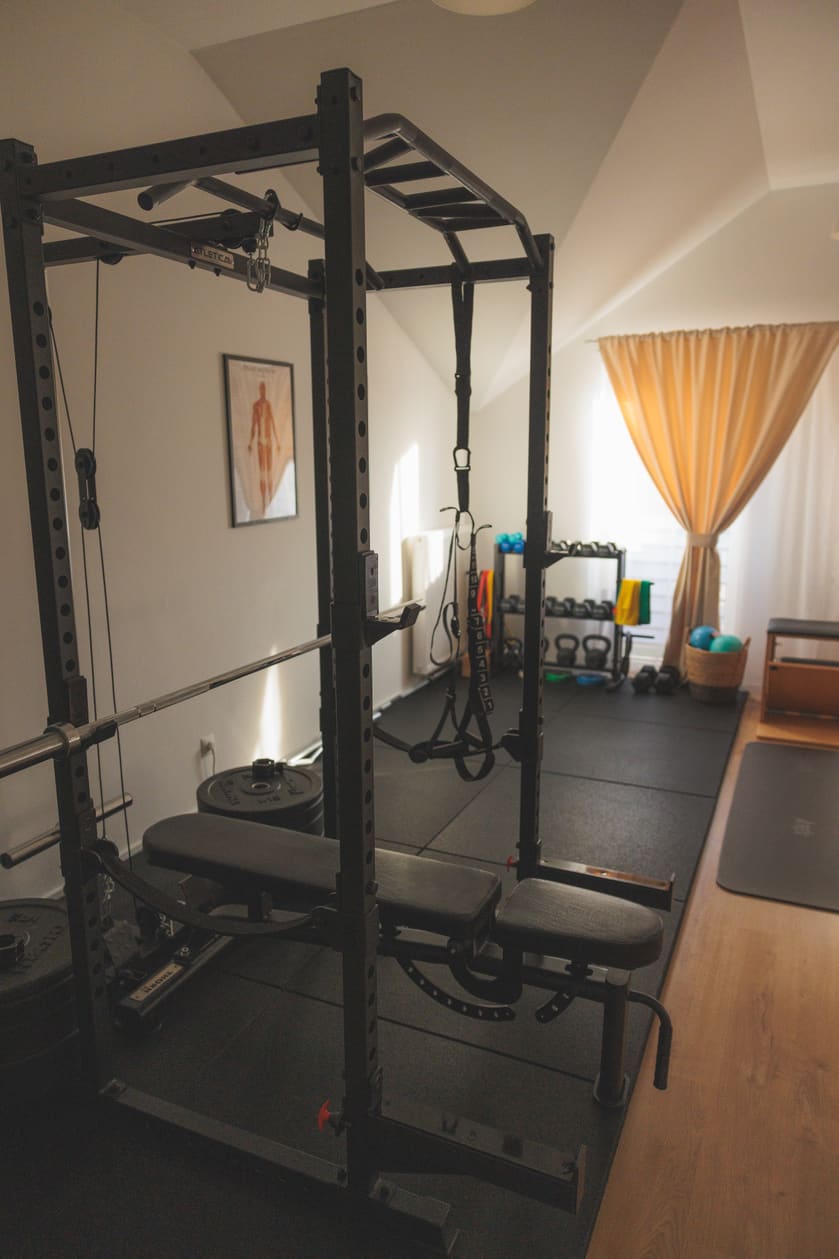 Strefa treningu siłowego w studio Atelier Ruchu — klatka, ławka i obciążenia